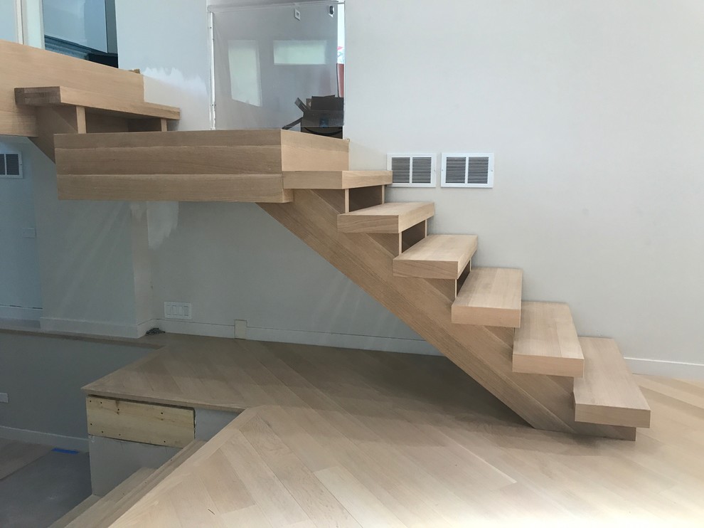 Small contemporary wood straight staircase in Chicago with open risers and glass railing.
