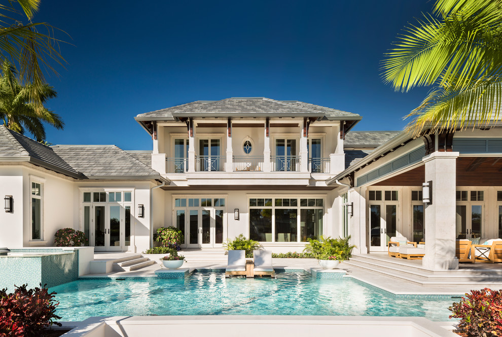This is an example of a beach style two-storey house exterior in Miami with a hip roof and a shingle roof.