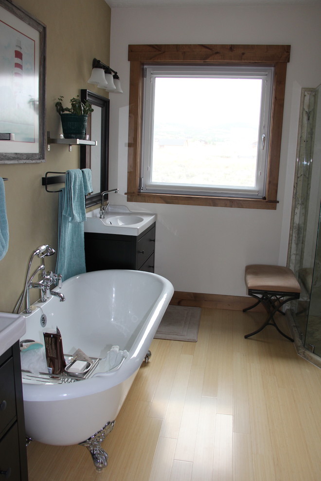 Photo of a mid-sized country master bathroom in Salt Lake City with a pedestal sink, dark wood cabinets, a claw-foot tub, a corner shower, a one-piece toilet, brown walls and bamboo floors.