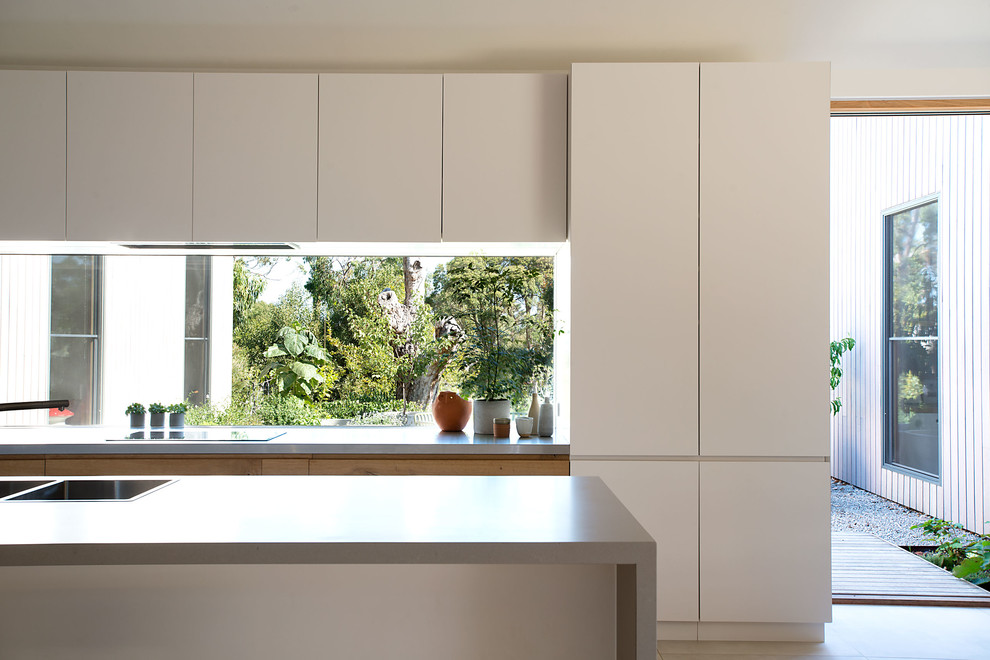 Inspiration for a large contemporary single-wall open plan kitchen in Melbourne with a double-bowl sink, white cabinets, solid surface benchtops, glass sheet splashback, stainless steel appliances, porcelain floors, with island, grey floor and grey benchtop.