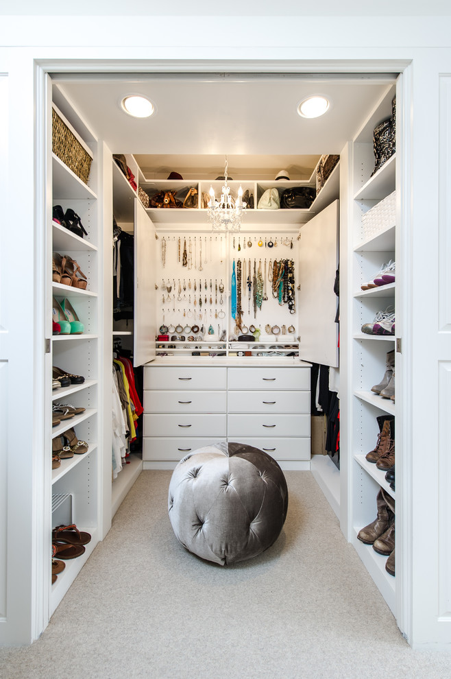 This is an example of a small traditional women's walk-in wardrobe in Los Angeles with raised-panel cabinets, white cabinets and carpet.