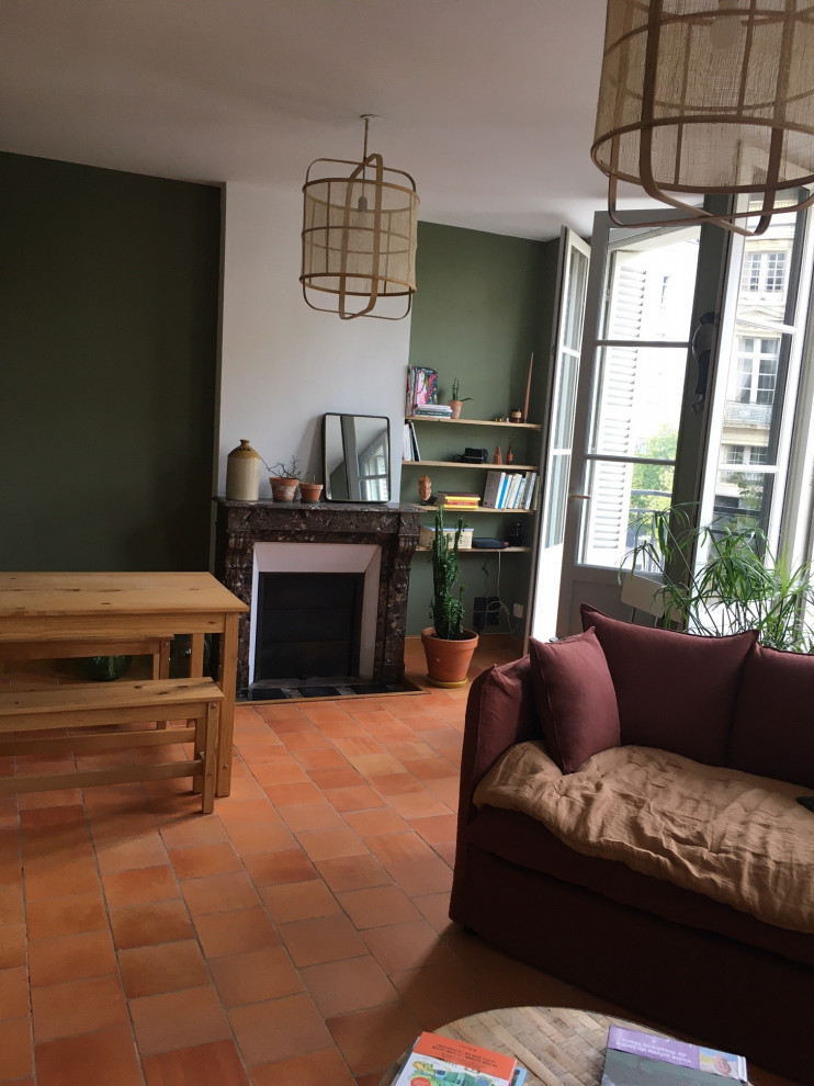 Идея дизайна: открытая гостиная комната среднего размера в стиле фьюжн с зелеными стенами, полом из терракотовой плитки, стандартным камином, фасадом камина из каменной кладки и оранжевым полом