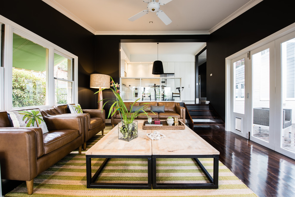 This is an example of a transitional enclosed living room in Sydney with black walls and dark hardwood floors.