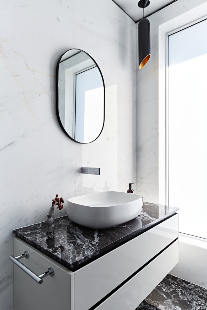 This is an example of a contemporary bathroom in Sydney with flat-panel cabinets, white cabinets, white tile, a vessel sink, black floor, black benchtops, a single vanity and a floating vanity.