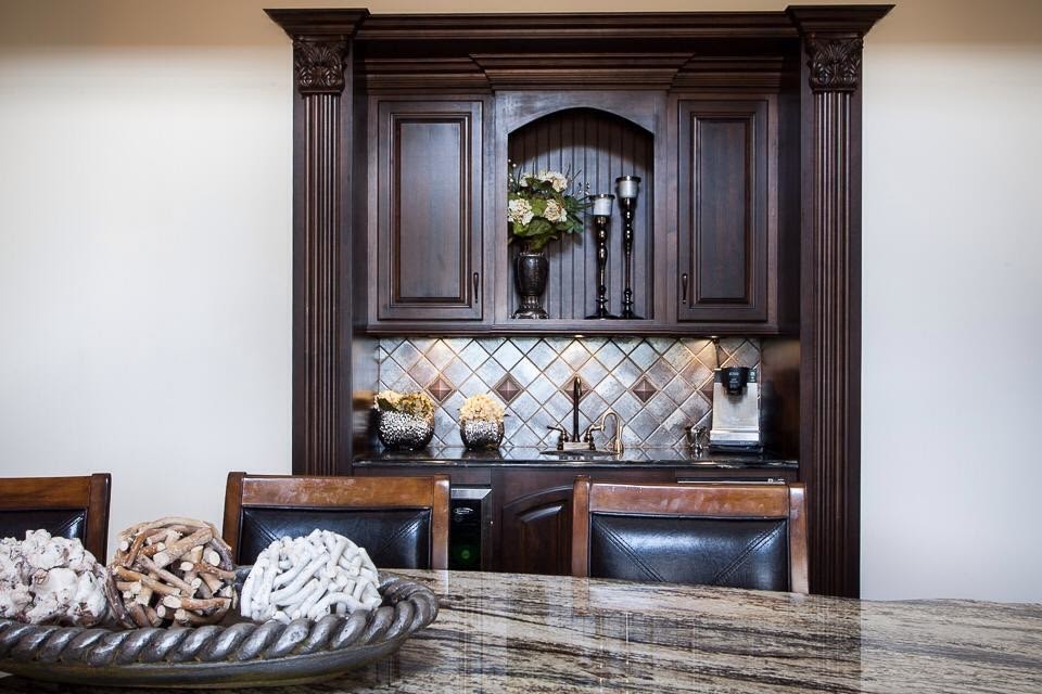 Large transitional l-shaped dark wood floor and brown floor eat-in kitchen photo in Birmingham with a farmhouse sink, raised-panel cabinets, white cabinets, brown backsplash, stainless steel appliances and an island