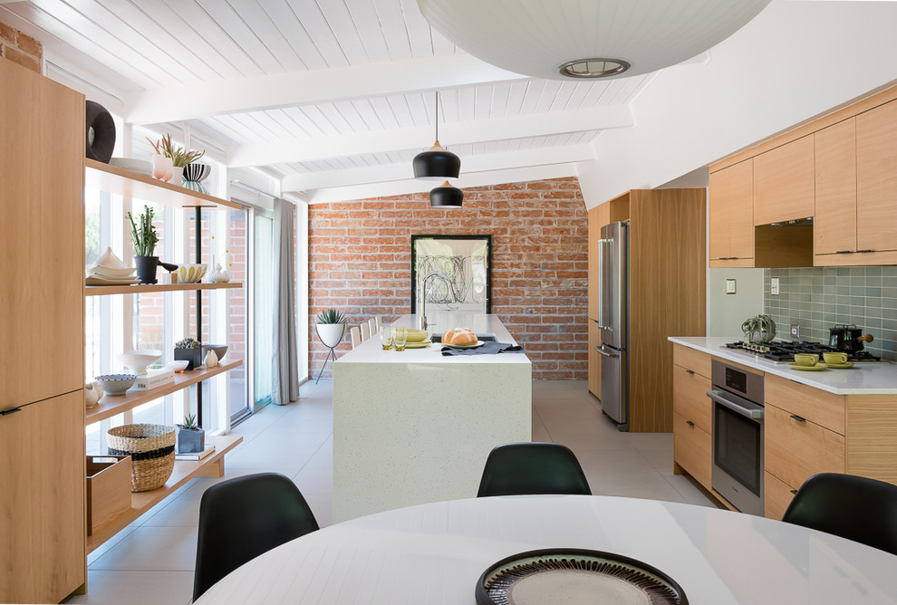 Photo of a mid-sized midcentury galley open plan kitchen in Other with an undermount sink, flat-panel cabinets, medium wood cabinets, quartz benchtops, green splashback, ceramic splashback, stainless steel appliances, porcelain floors, with island and grey floor.