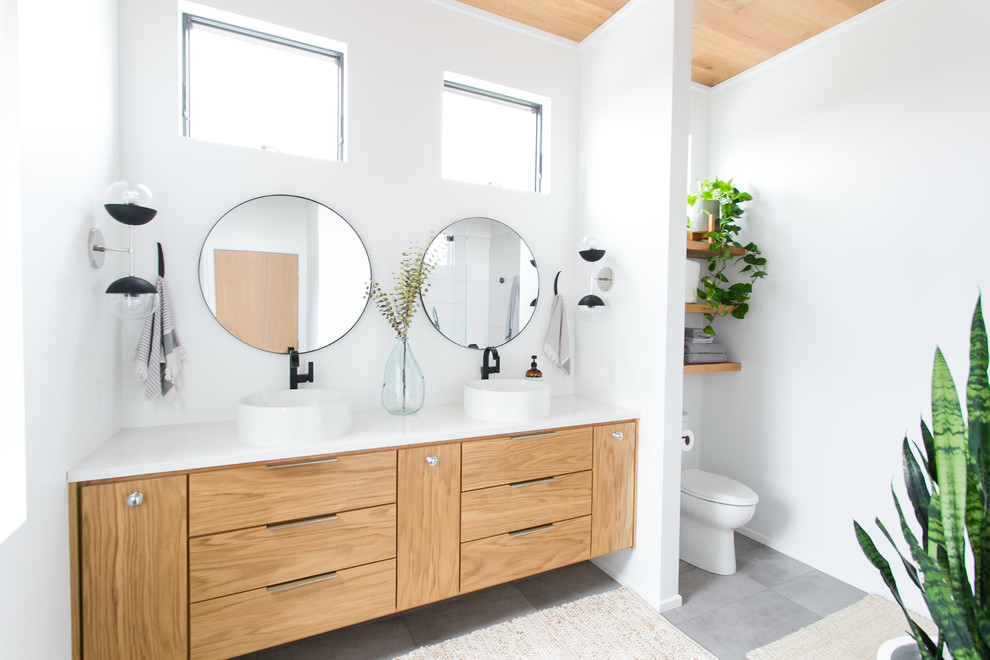 This is an example of a mid-sized contemporary master bathroom in Cleveland with flat-panel cabinets, light wood cabinets, a two-piece toilet, white walls, porcelain floors, a vessel sink, engineered quartz benchtops, grey floor and white benchtops.