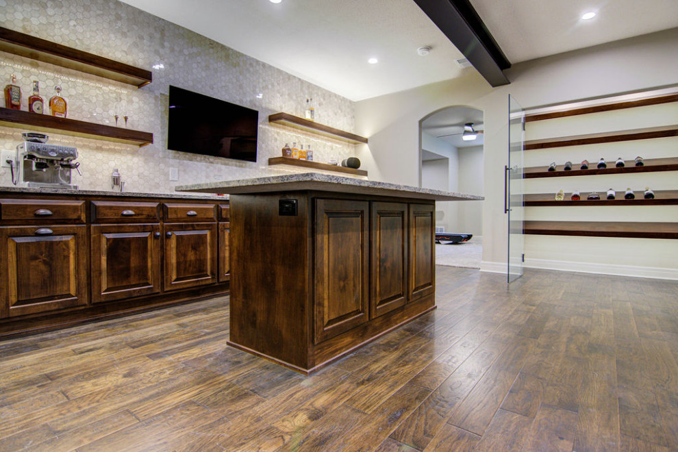 Design ideas for a large classic fully buried basement in Kansas City with a home bar, beige walls, medium hardwood flooring, a tiled fireplace surround and brown floors.