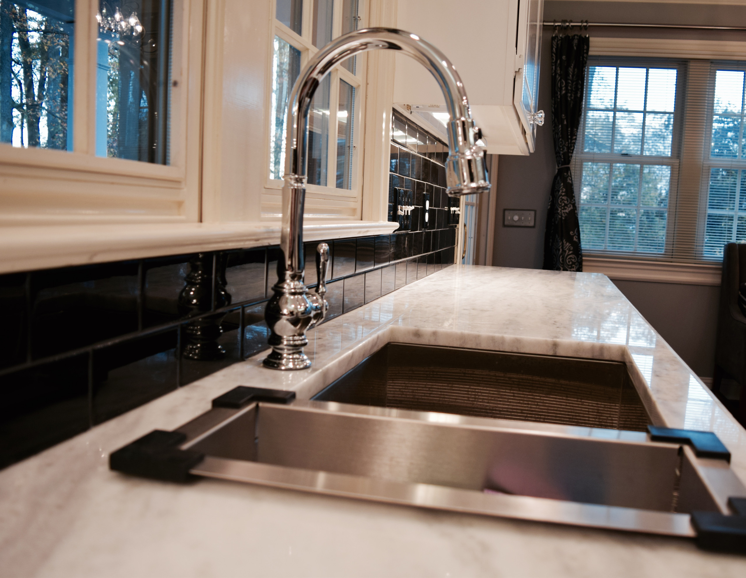 Goose neck chrome faucet with tile back splash and granite tops.