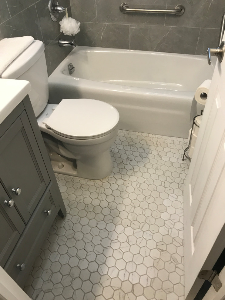 Photo of a small master bathroom in New York with furniture-like cabinets, grey cabinets, an alcove tub, an alcove shower, a two-piece toilet, gray tile, porcelain tile, white walls, porcelain floors, a drop-in sink, quartzite benchtops, multi-coloured floor, a shower curtain, white benchtops, a single vanity, a built-in vanity and decorative wall panelling.