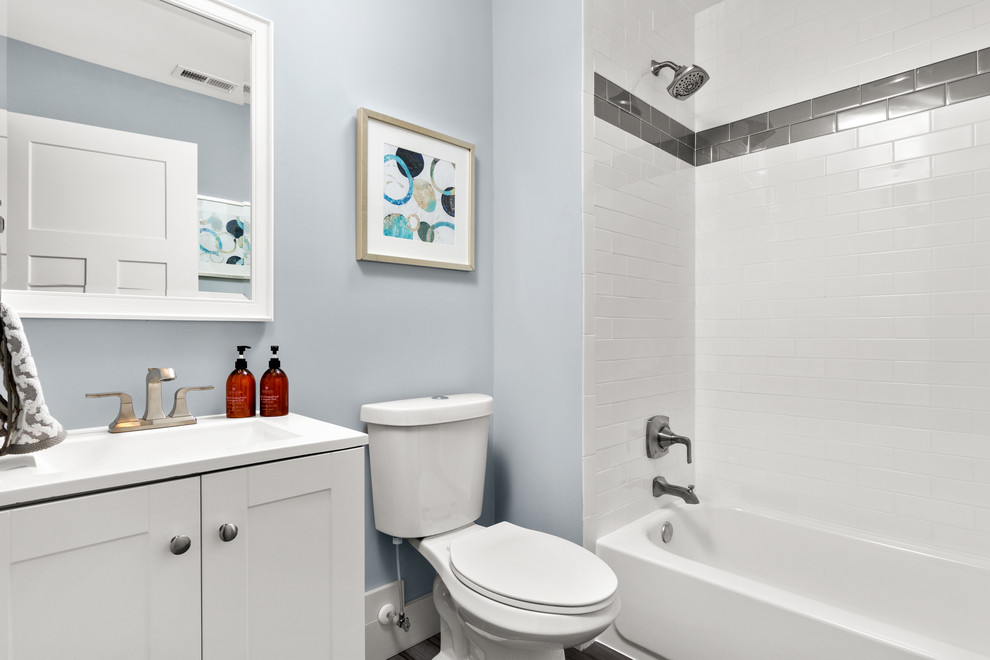 Inspiration for a mid-sized arts and crafts kids bathroom in Baltimore with shaker cabinets, white cabinets, an alcove tub, a shower/bathtub combo, a two-piece toilet, white tile, subway tile, grey walls, ceramic floors, an integrated sink, solid surface benchtops, grey floor, an open shower and white benchtops.