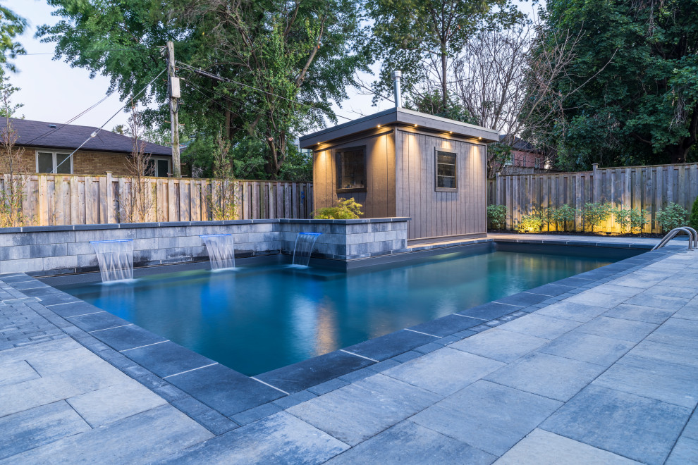 Example of a mid-sized transitional backyard concrete paver and l-shaped lap pool fountain design in Toronto