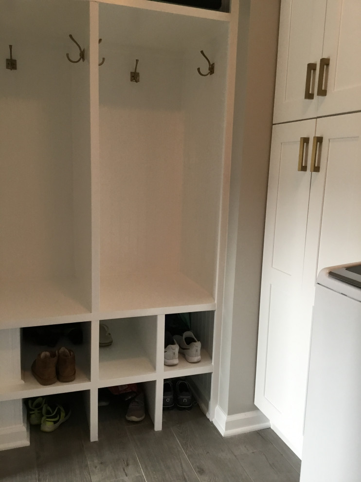 Photo of a small modern dedicated laundry room in New York with shaker cabinets, white cabinets, grey splashback, ceramic splashback, grey walls, ceramic floors, a side-by-side washer and dryer and grey floor.
