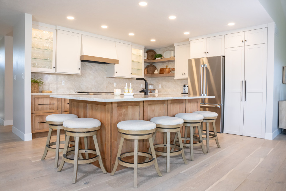 Mid-sized transitional l-shaped open plan kitchen in Other with an undermount sink, shaker cabinets, white cabinets, stainless steel appliances, with island, brown floor and vaulted.