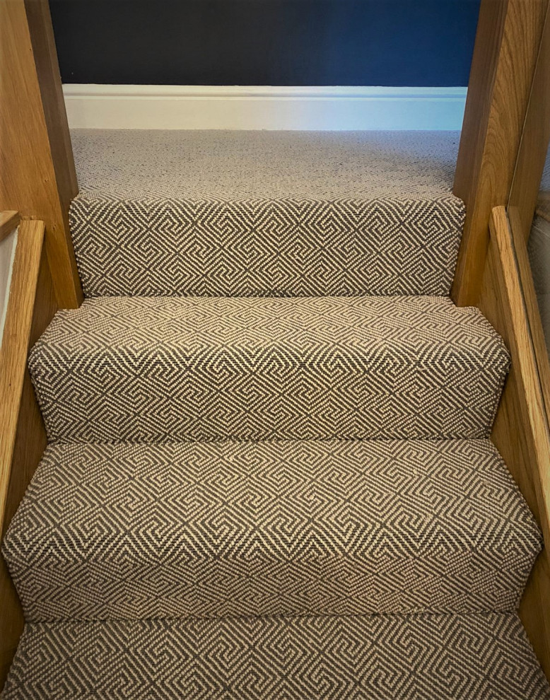 Design ideas for a mid-sized contemporary carpeted straight staircase in Hertfordshire with carpet risers and wood railing.