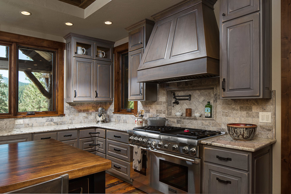 Kitchen - large rustic l-shaped dark wood floor kitchen idea with a farmhouse sink, raised-panel cabinets, distressed cabinets, brown backsplash, paneled appliances, an island and wood countertops