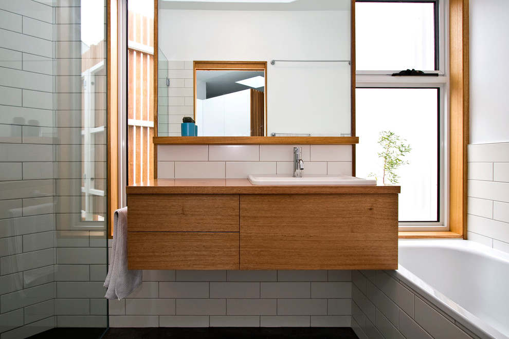 Photo of a mid-sized contemporary bathroom in Hobart with a drop-in sink, flat-panel cabinets, medium wood cabinets, wood benchtops, a drop-in tub, a corner shower, white tile, ceramic tile, white walls and ceramic floors.