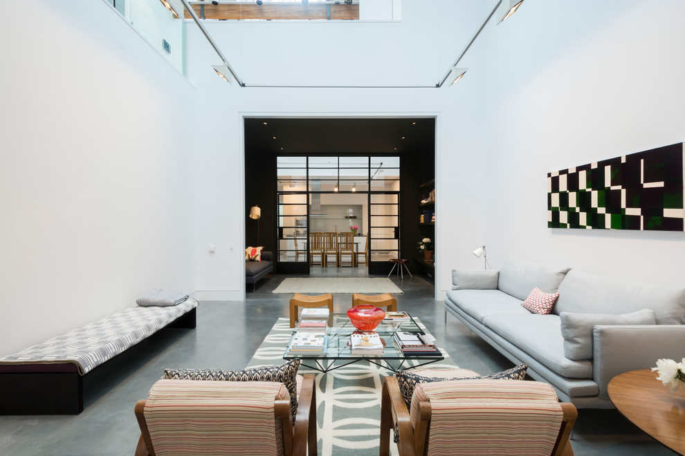 Large industrial living room in London with a library, white walls and concrete floors.