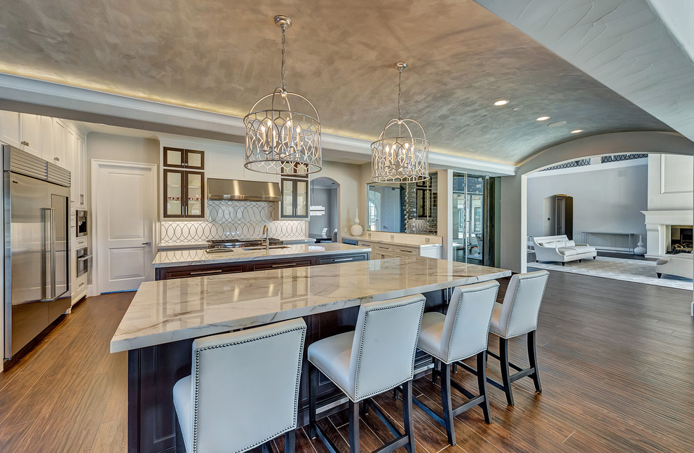 Huge transitional u-shaped ceramic tile and brown floor eat-in kitchen photo in Orange County with an undermount sink, shaker cabinets, white cabinets, marble countertops, white backsplash, marble backsplash, stainless steel appliances and two islands
