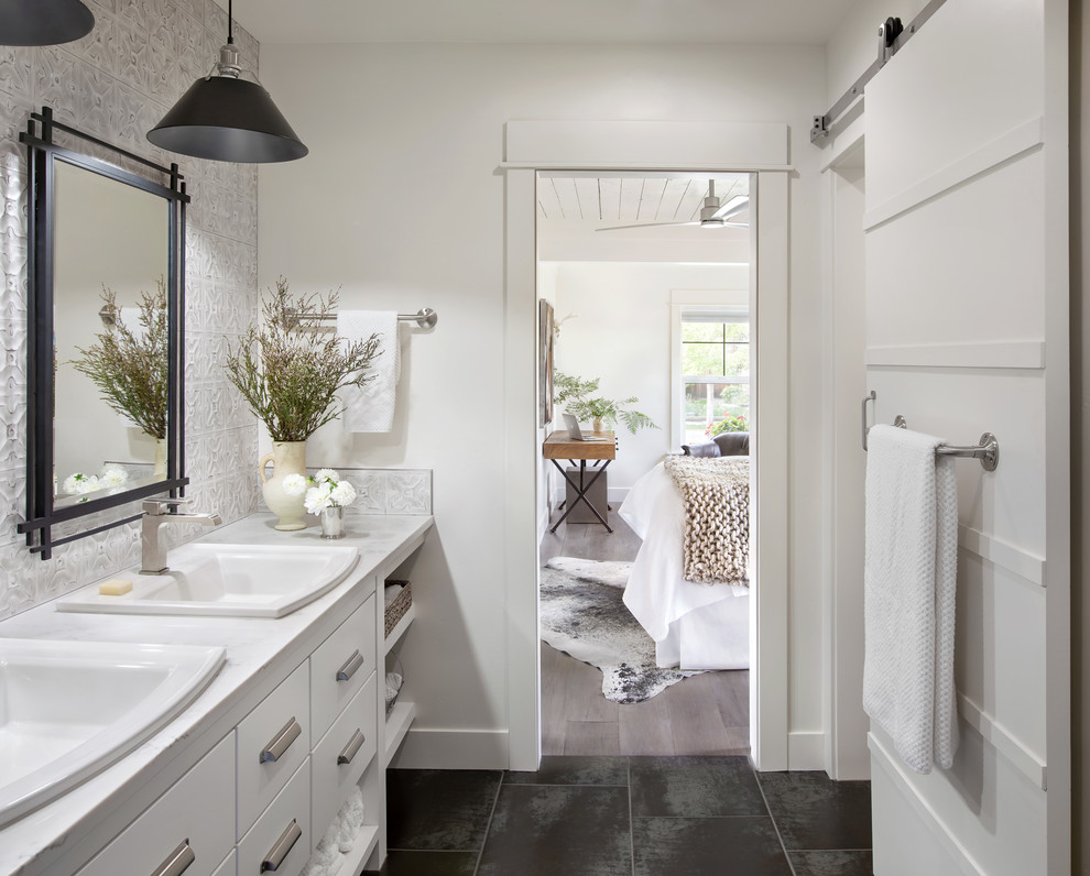 This is an example of a country master bathroom in Other with flat-panel cabinets, white cabinets, white walls, a drop-in sink, black floor and grey benchtops.