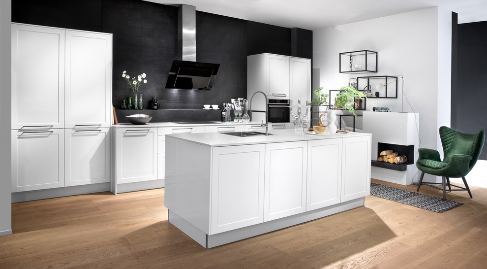 Offene, Große Country Küche in L-Form mit Schrankfronten mit vertiefter Füllung, weißen Schränken, Quarzit-Arbeitsplatte, Küchenrückwand in Weiß, Glasrückwand, schwarzen Elektrogeräten, Kücheninsel und weißer Arbeitsplatte in Hannover
