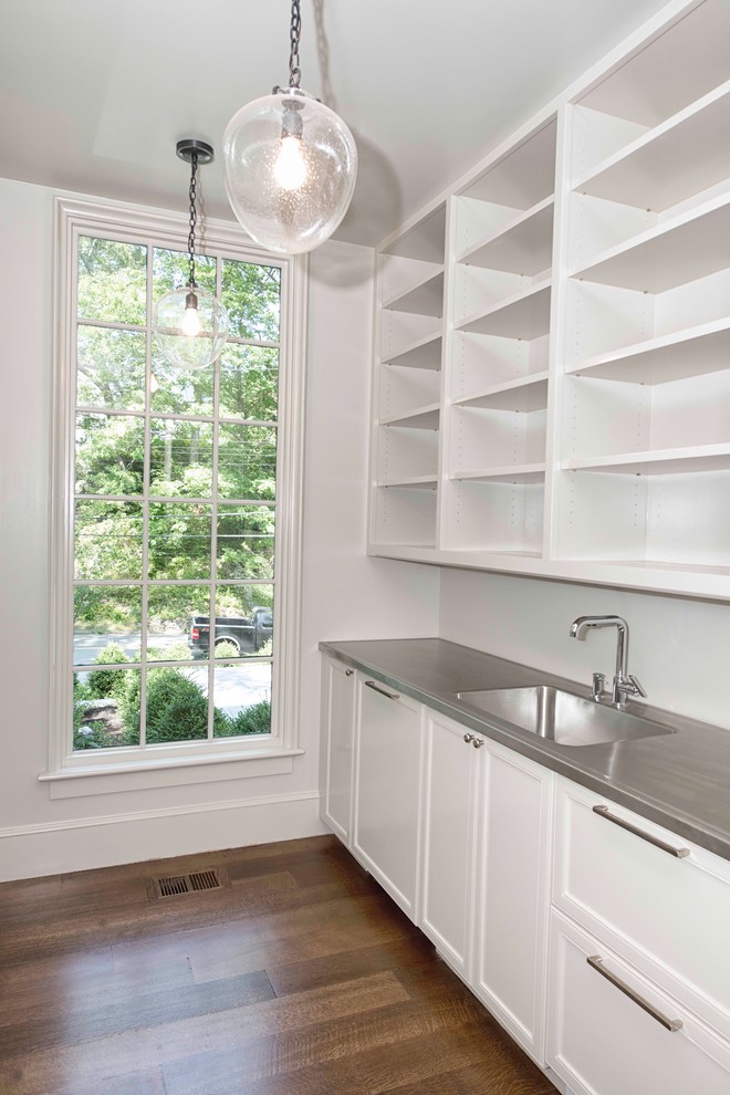 Inspiration for a transitional galley kitchen in New York with recessed-panel cabinets, white cabinets, medium hardwood floors, an integrated sink, stainless steel benchtops and white splashback.