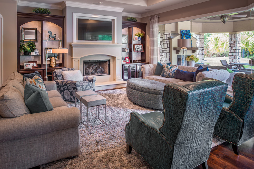 Inspiration for a large transitional open concept living room in Houston with grey walls, medium hardwood floors, a standard fireplace, a plaster fireplace surround, a wall-mounted tv and brown floor.
