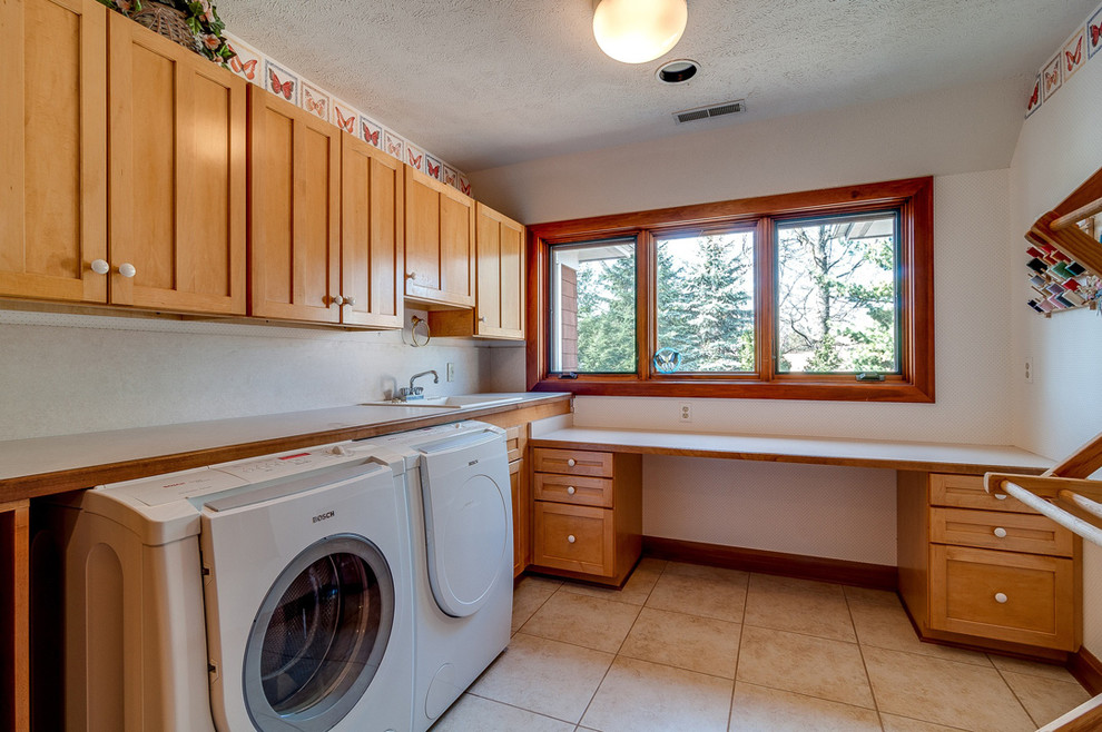 Design ideas for a mid-sized arts and crafts l-shaped dedicated laundry room in Chicago with a drop-in sink, shaker cabinets, medium wood cabinets, laminate benchtops, white walls, ceramic floors and a side-by-side washer and dryer.