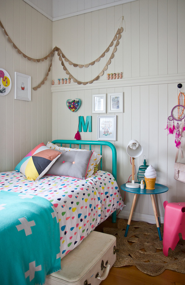 This is an example of an eclectic kids' bedroom for girls in Brisbane with beige walls and medium hardwood floors.