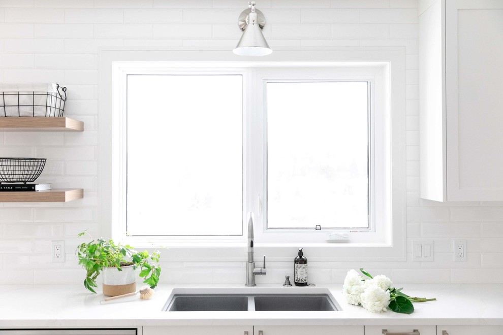 Example of a large transitional u-shaped medium tone wood floor and brown floor eat-in kitchen design in Calgary with an undermount sink, shaker cabinets, white cabinets, quartzite countertops, white backsplash, subway tile backsplash, stainless steel appliances, an island and white countertops