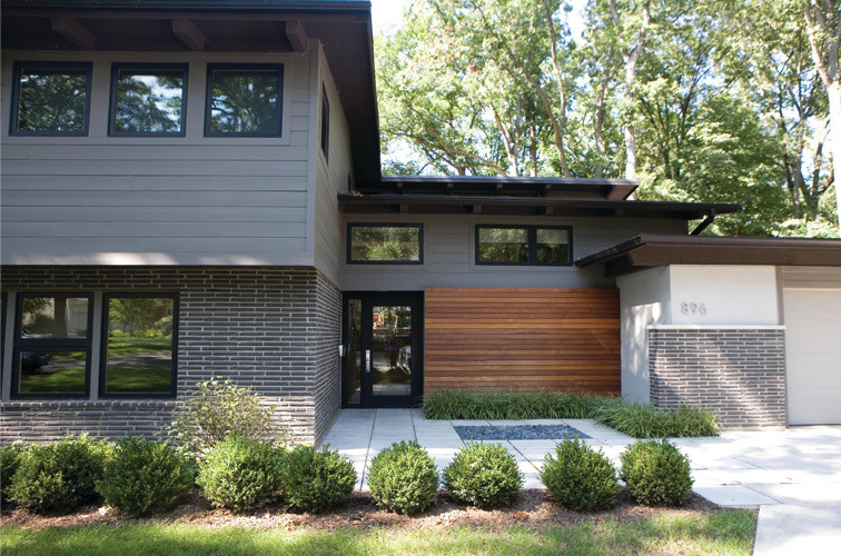 Photo of a large midcentury two-storey grey exterior in Chicago with mixed siding and a flat roof.