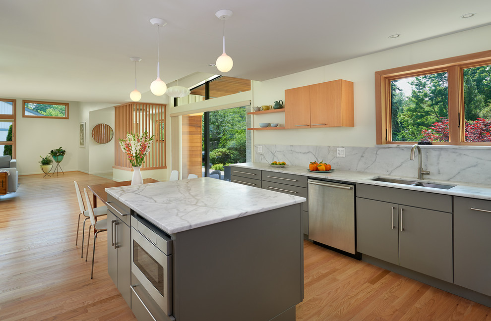 This is an example of a mid-sized midcentury l-shaped eat-in kitchen in DC Metro with an undermount sink, flat-panel cabinets, grey cabinets, marble benchtops, white splashback, stone slab splashback, stainless steel appliances, light hardwood floors, with island and beige floor.