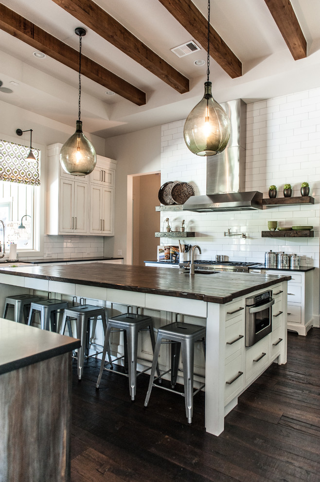 Design ideas for a transitional u-shaped kitchen in Austin with shaker cabinets, white cabinets, white splashback, subway tile splashback, stainless steel appliances and wood benchtops.