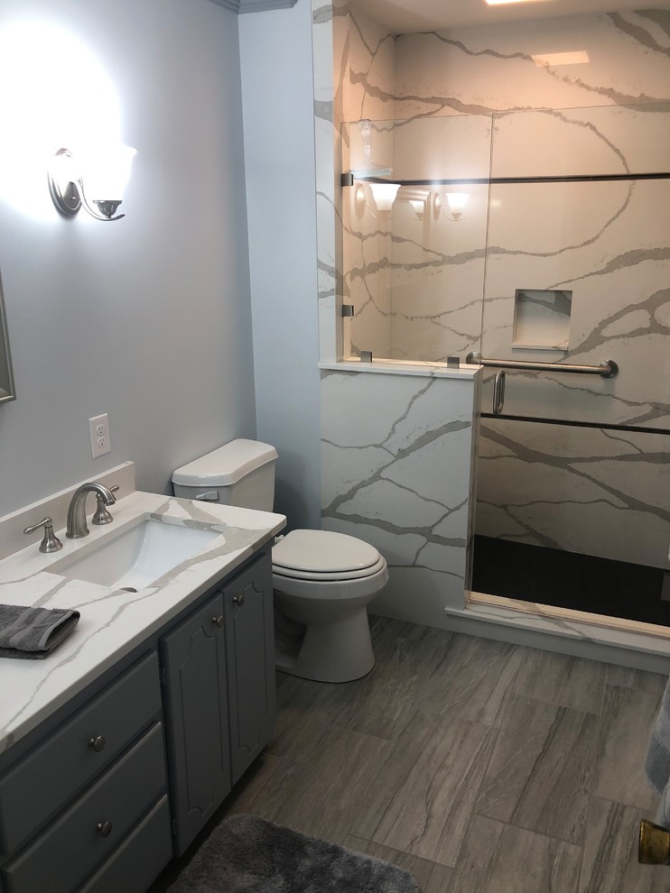 Photo of a contemporary bathroom in Other with flat-panel cabinets, grey cabinets, an alcove shower, a two-piece toilet, white tile, stone slab, white walls, an undermount sink, quartzite benchtops, a hinged shower door and white benchtops.