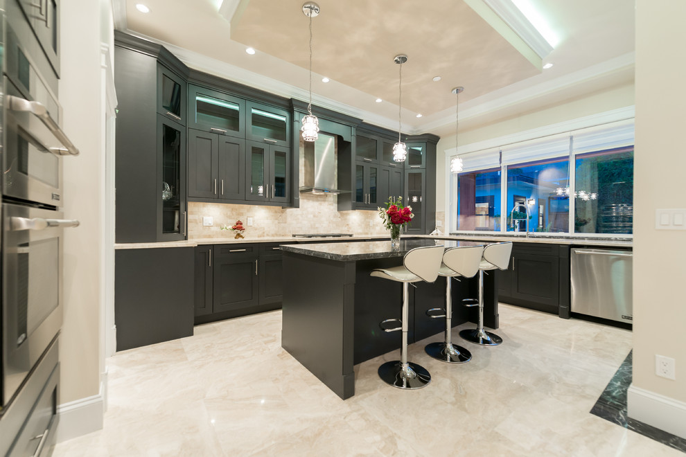 Large contemporary u-shaped open plan kitchen in Vancouver with an undermount sink, shaker cabinets, black cabinets, granite benchtops, beige splashback, stone tile splashback, stainless steel appliances, marble floors, with island, beige floor and multi-coloured benchtop.