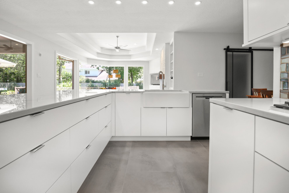 Large contemporary l-shaped open plan kitchen in Houston with a farmhouse sink, flat-panel cabinets, white cabinets, quartzite benchtops, multi-coloured splashback, glass tile splashback, stainless steel appliances, cement tiles, with island, grey floor and grey benchtop.