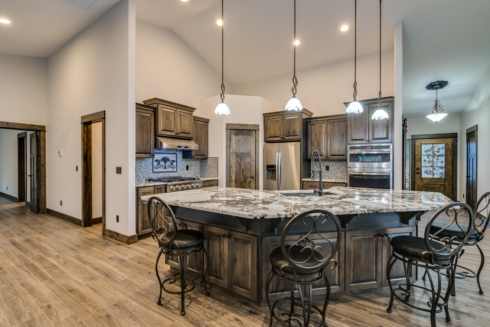 Inspiration for a large rustic u-shaped laminate floor and brown floor open concept kitchen remodel with an undermount sink, raised-panel cabinets, medium tone wood cabinets, quartz countertops, mosaic tile backsplash, stainless steel appliances and an island