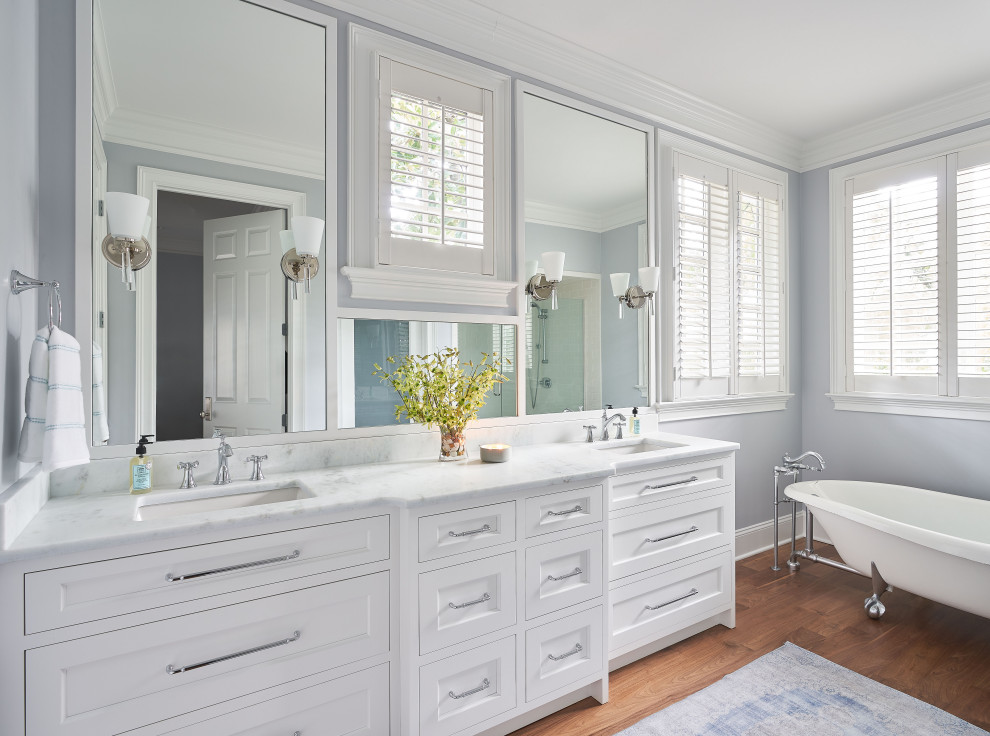 Exemple d'une salle de bain chic avec une baignoire sur pieds, un sol en bois brun, un plan de toilette en marbre et meuble double vasque.