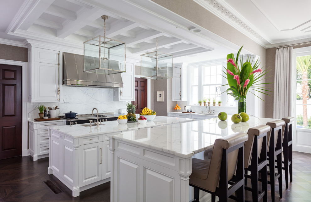 Inspiration for a large transitional l-shaped brown floor kitchen remodel with an undermount sink, raised-panel cabinets, white cabinets, white backsplash, stainless steel appliances, two islands and white countertops