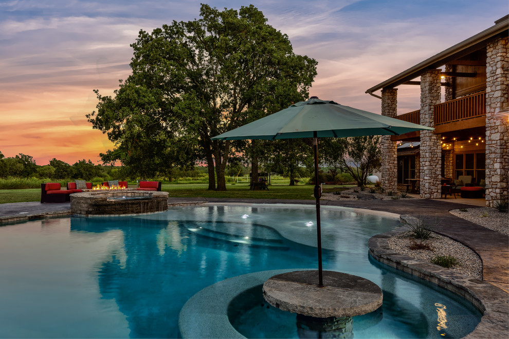 This is an example of an expansive arts and crafts backyard custom-shaped pool in Dallas with a hot tub and stamped concrete.