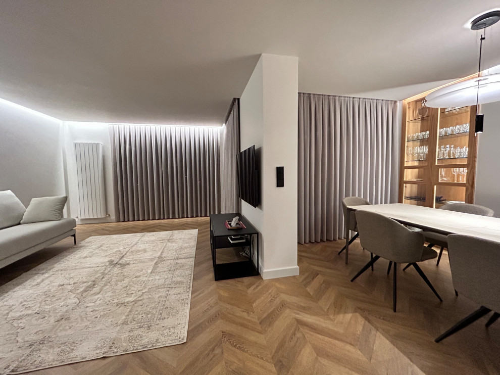 На фото: гостиная комната среднего размера в современном стиле с полом из ламината, телевизором на стене и ковром на полу