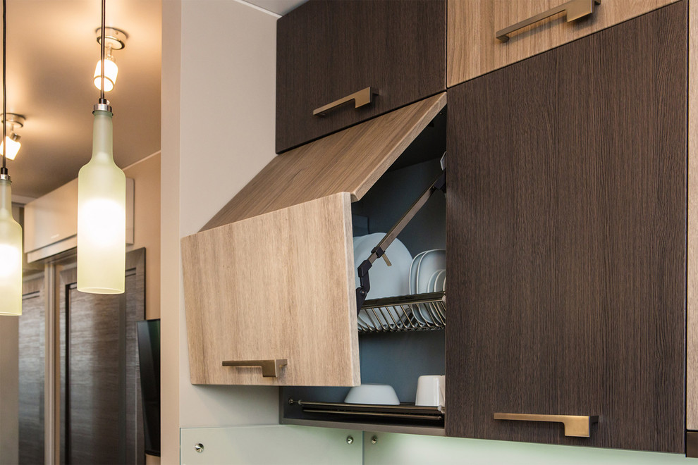 Photo of a small modern galley eat-in kitchen in Novosibirsk with a drop-in sink, flat-panel cabinets, light wood cabinets, solid surface benchtops, glass sheet splashback, black appliances, a peninsula and white benchtop.
