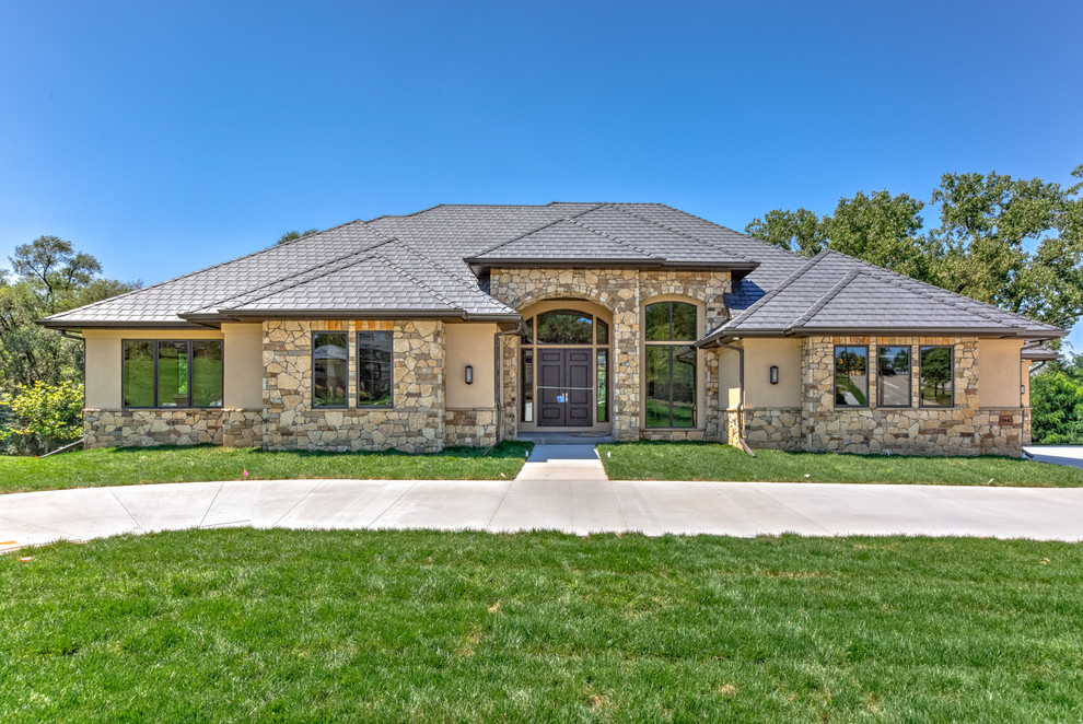 Inspiration for an expansive contemporary one-storey beige exterior in Omaha with stone veneer.