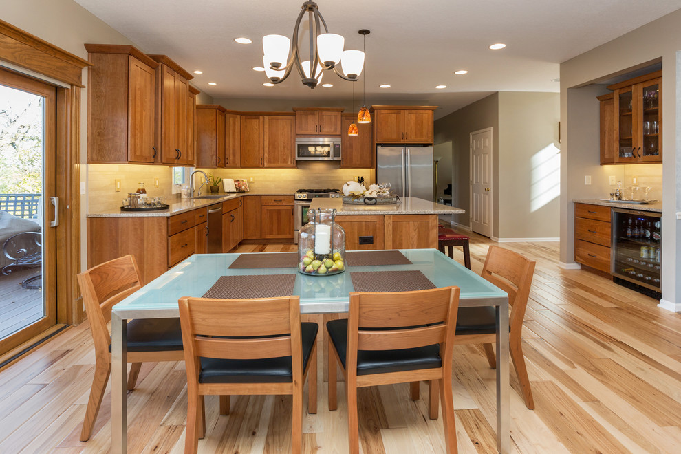 Example of a mid-sized transitional l-shaped light wood floor open concept kitchen design with an undermount sink, recessed-panel cabinets, medium tone wood cabinets, quartz countertops, beige backsplash, stone tile backsplash, stainless steel appliances and an island