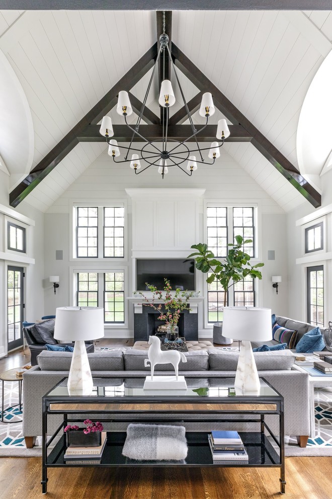 Design ideas for a large transitional open concept family room in Chicago with white walls, medium hardwood floors, a standard fireplace, a wall-mounted tv and brown floor.