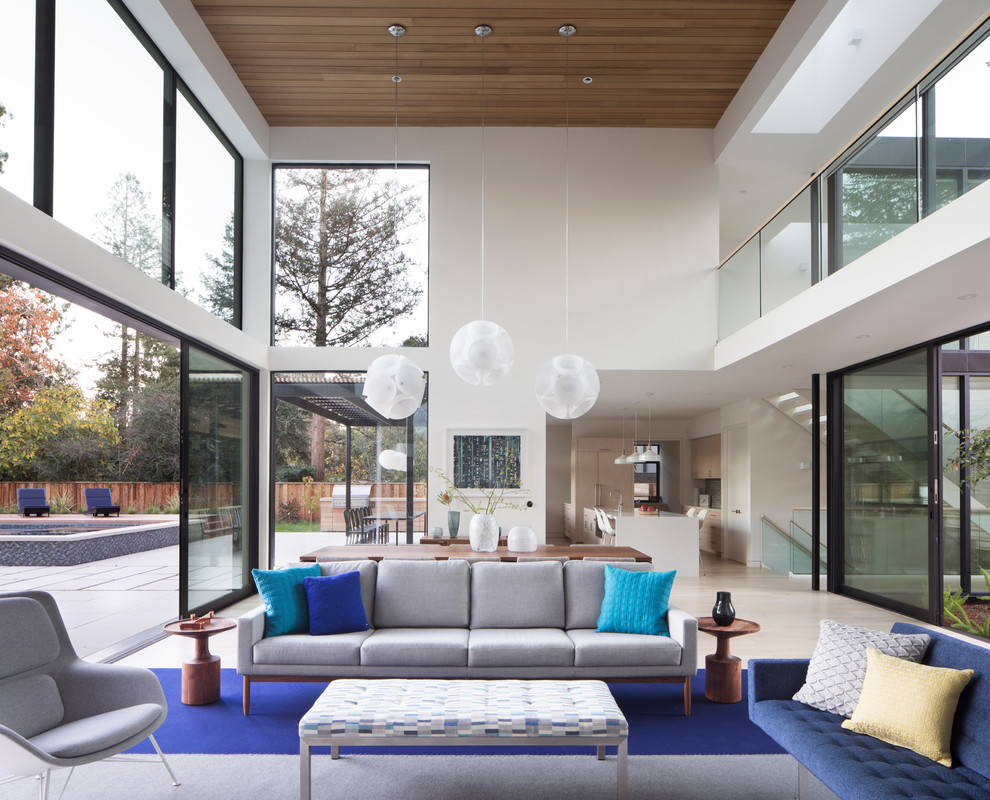 This is an example of an expansive contemporary open concept living room in San Francisco with light hardwood floors, white walls and beige floor.