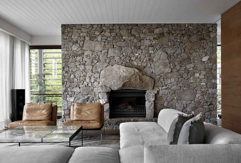 Inspiration for a contemporary living room in Melbourne with white walls, a stone fireplace surround, grey floor and a standard fireplace.