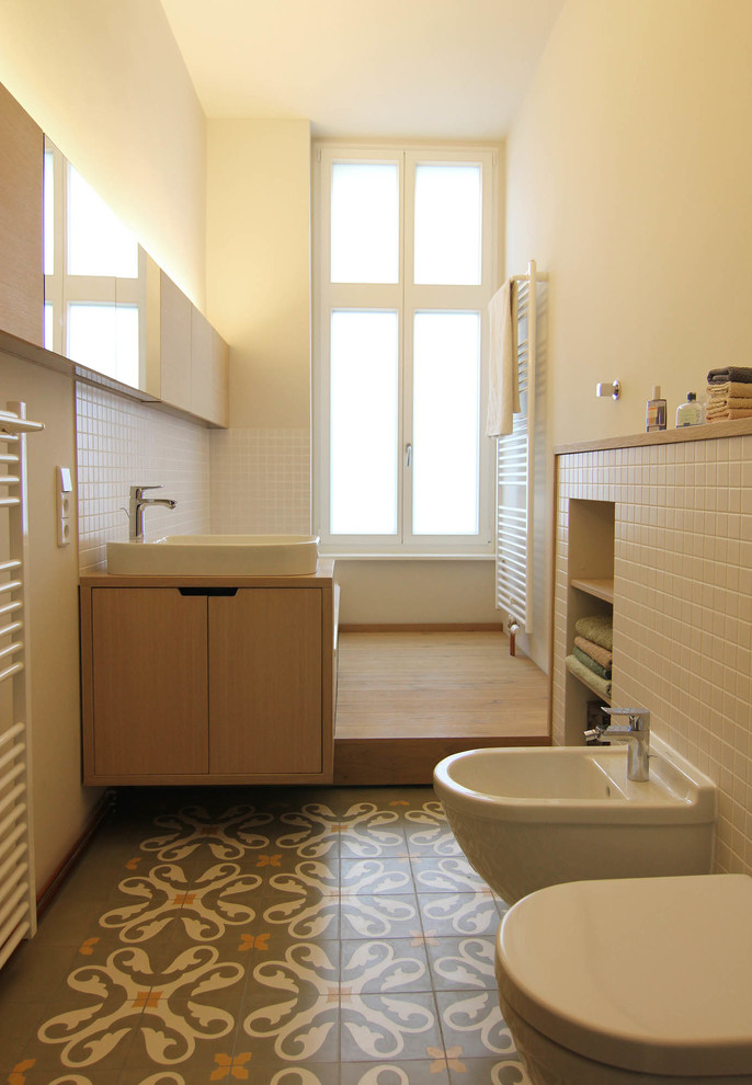 Photo of a mid-sized contemporary bathroom in Berlin with flat-panel cabinets, medium wood cabinets, a bidet, white tile, beige walls, a vessel sink and wood benchtops.