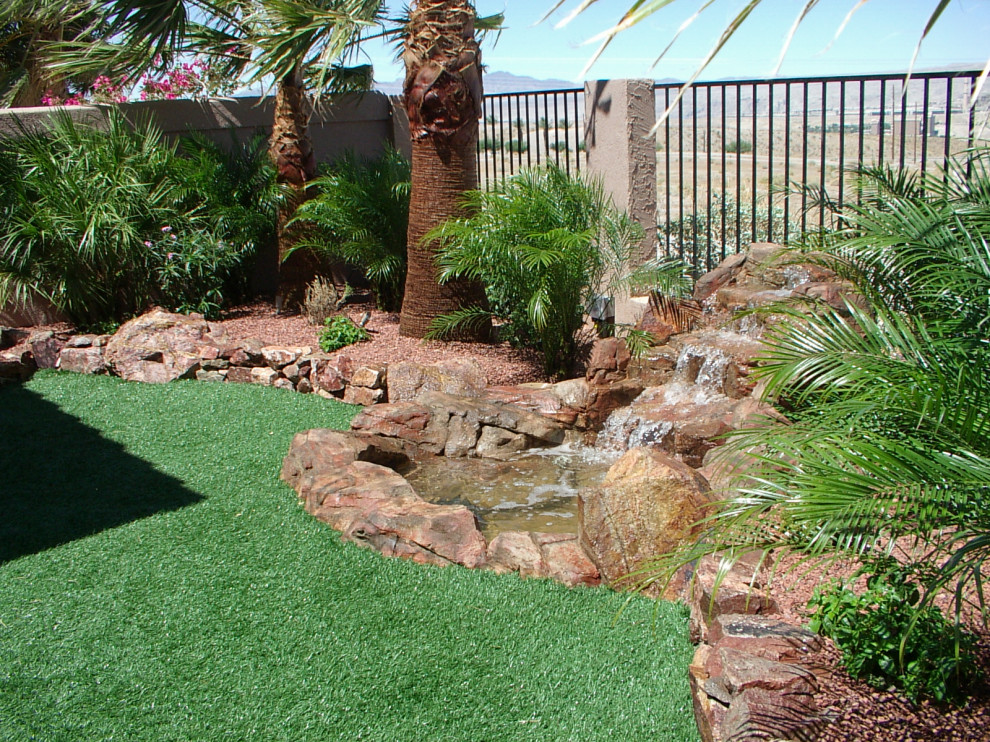 Medium sized world-inspired front xeriscape full sun garden for summer in Other with a desert look, natural stone paving and a stone fence.