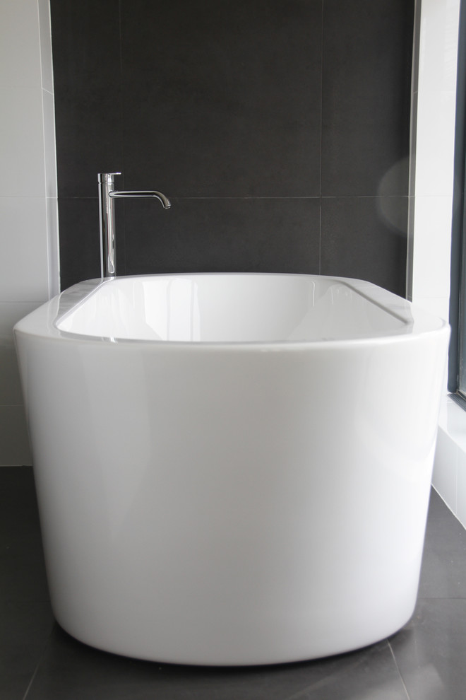 This is an example of an expansive traditional bathroom in Perth with white cabinets, a freestanding tub, black tile and white walls.
